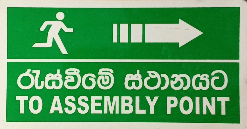 Bilingual Sinhala and English directional sign to assembly point